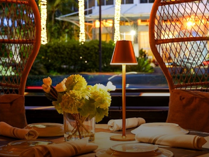 Baires Grill – Sunny Isles: a warmly lit dining table with flowers and woven chairs